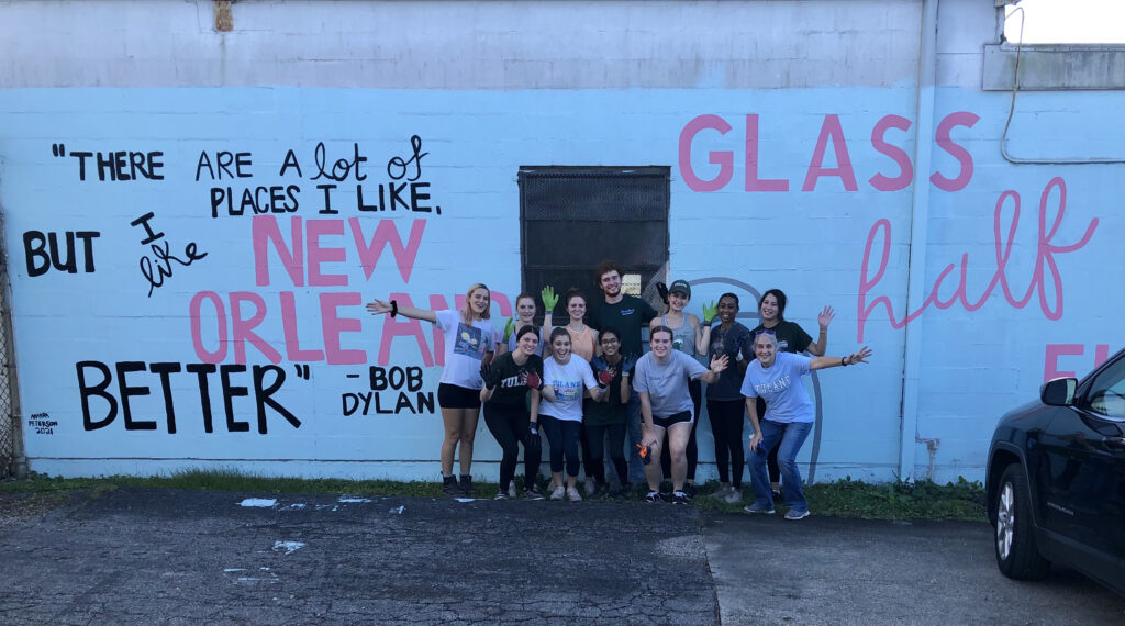 Group of Tulane students, staff, and faculty with Fran from Glass Half Full Nola are standing in front of the Glass Half Full Nola warehouse